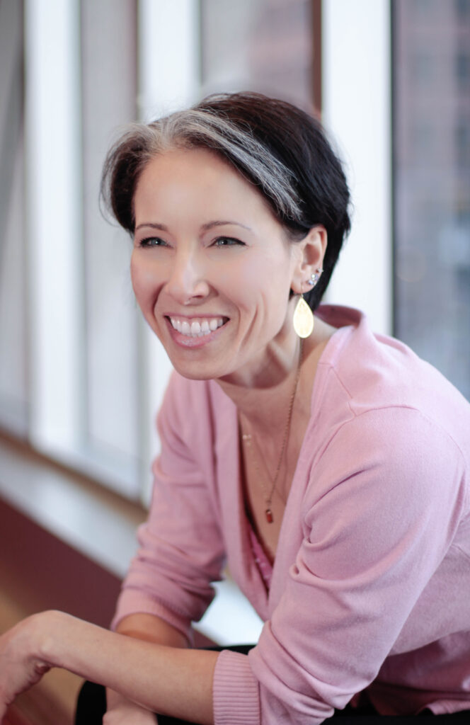 Portrait of a woman laughing while leaning on a stone ledge