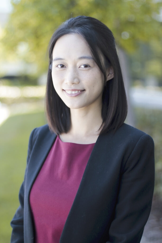Professional headshot of a woman in a blazer beside a lake